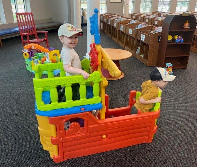 Robyn Kelly's children playing on a toy boat in the children's area of Florence-Lauderdale Public Library