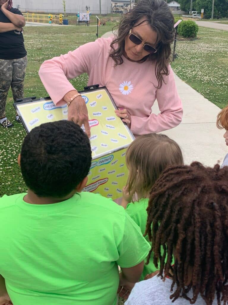 Town Creek Public Library director Sharon Green leads children in an activity at the library's outdoor Story Walk.